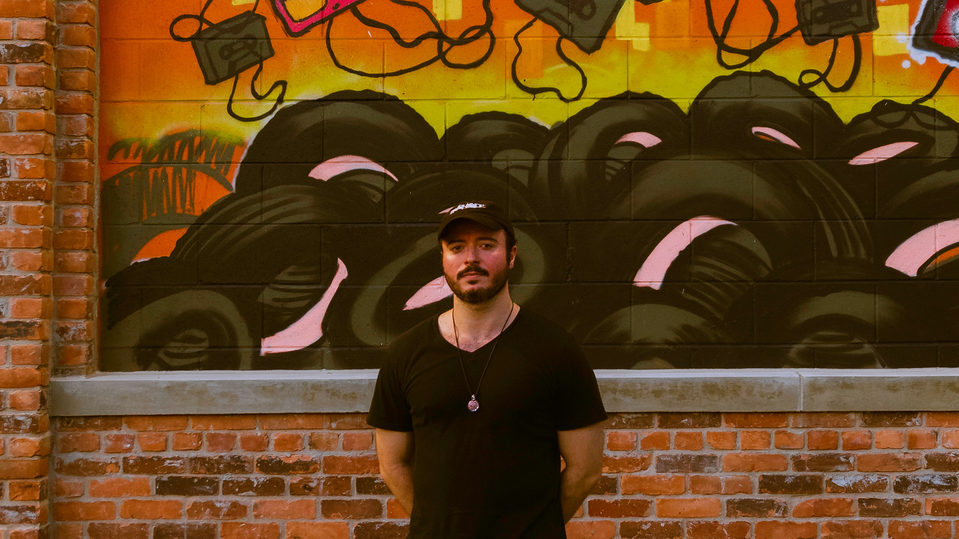 Evan standing in front of a street-art backdrop
